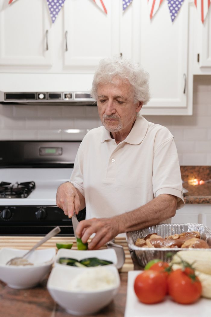 Services Senior man preparing vegetables at home kitchen counter for a meal.